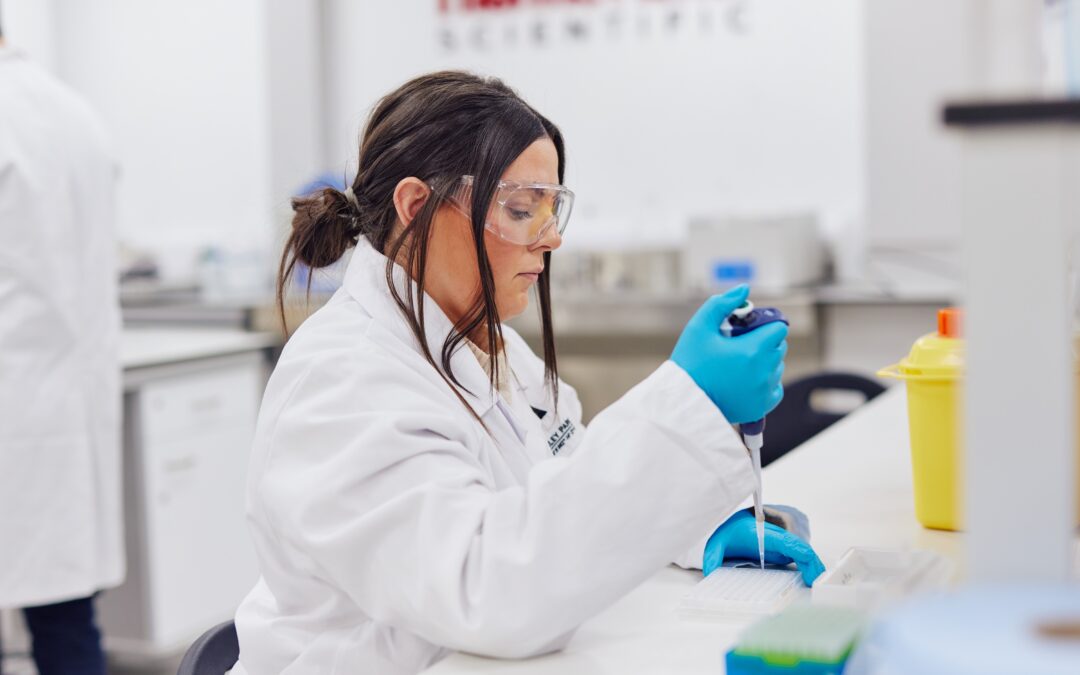woman in lab coat working with pipette in laboratory