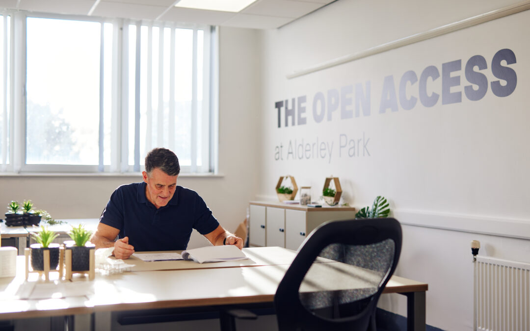 man sat at desk in front of the open access sign