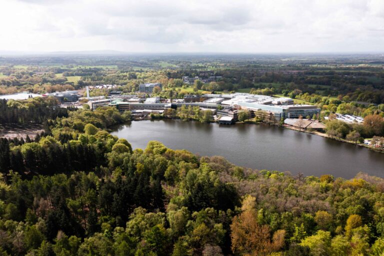 drone view of alderley park campus with lake in foreground